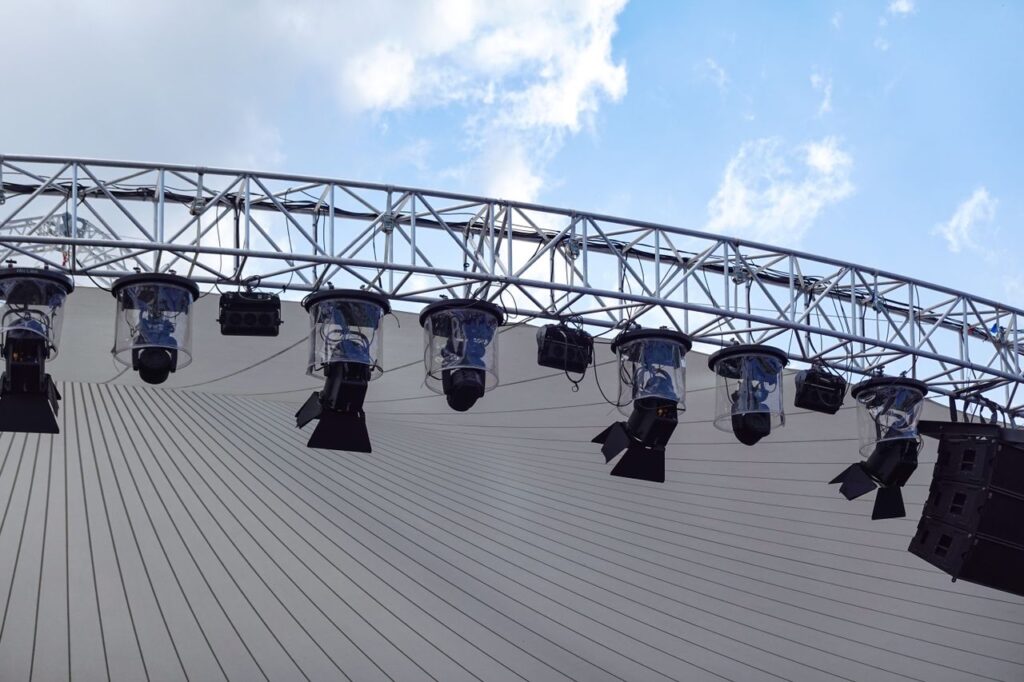 pexels photo 12787862 12787862 Overhead view of an outdoor stage with modern lighting setup against a blue sky.